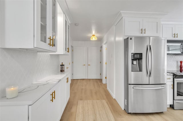 kitchen featuring light stone countertops, appliances with stainless steel finishes, backsplash, white cabinets, and light hardwood / wood-style flooring