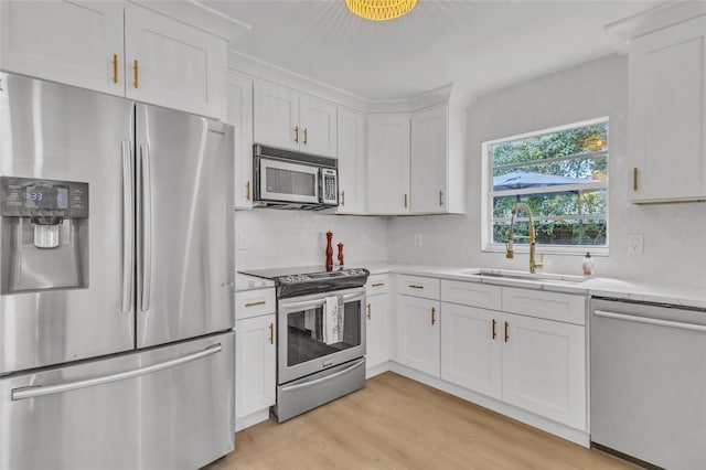 kitchen with sink, white cabinets, stainless steel appliances, and light hardwood / wood-style floors