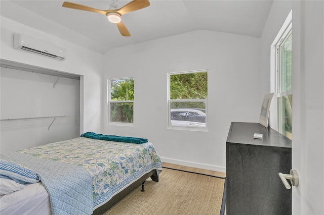 bedroom featuring a wall unit AC, a closet, vaulted ceiling, light hardwood / wood-style floors, and ceiling fan