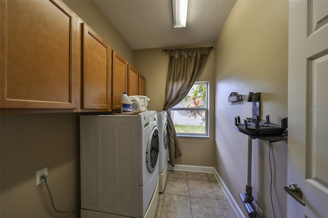 laundry room with cabinets, washing machine and dryer, light tile patterned floors, and a textured ceiling