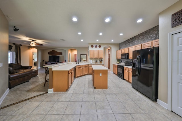 kitchen with a kitchen bar, kitchen peninsula, light tile patterned floors, and black appliances