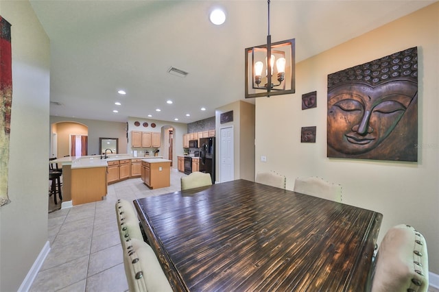 dining space with light tile patterned flooring, sink, and an inviting chandelier