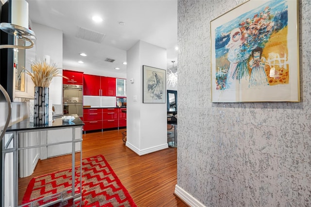 hallway featuring baseboards, recessed lighting, wood finished floors, and visible vents