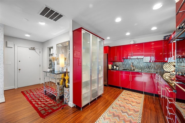kitchen with red cabinets, visible vents, tasteful backsplash, wood finished floors, and recessed lighting