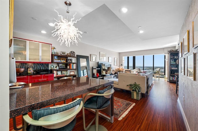 kitchen with dark wood-type flooring, recessed lighting, a breakfast bar, and an inviting chandelier