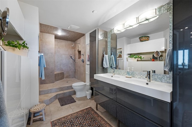 bathroom featuring a tile shower, vanity, toilet, and tile patterned flooring