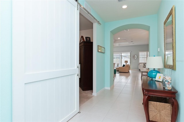 corridor with a barn door and light tile patterned flooring