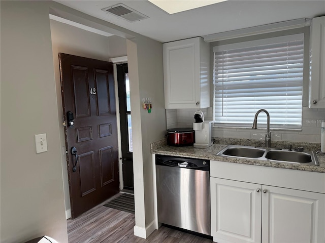 kitchen featuring tasteful backsplash, white cabinetry, stainless steel dishwasher, light hardwood / wood-style flooring, and sink