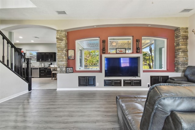 living room with ornate columns, wood-type flooring, and a healthy amount of sunlight