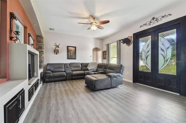 living room featuring light hardwood / wood-style flooring, a textured ceiling, and ceiling fan