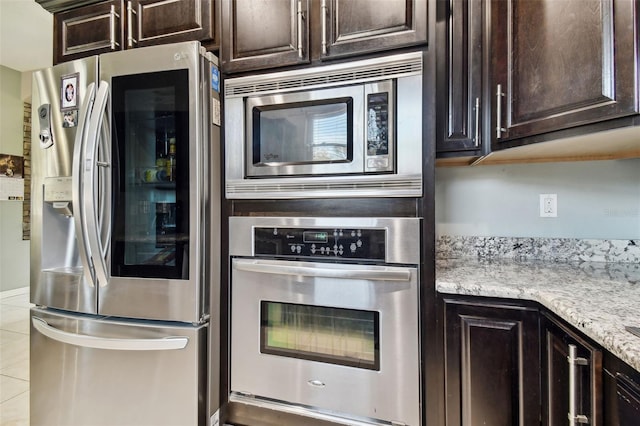 kitchen with light stone counters, appliances with stainless steel finishes, dark brown cabinetry, and light tile patterned floors