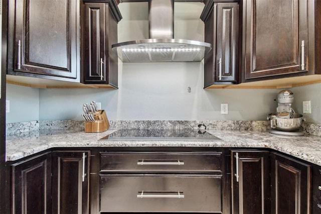 kitchen with black electric stovetop, wall chimney range hood, and dark brown cabinets