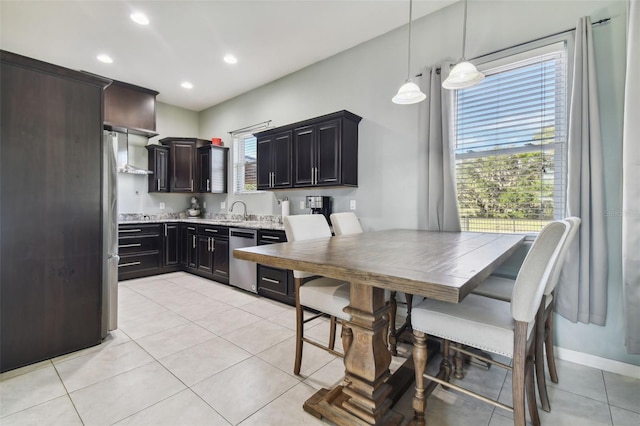 kitchen with light stone countertops, sink, dishwasher, decorative light fixtures, and light tile patterned floors