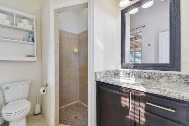 bathroom with vanity, toilet, a tile shower, and tile patterned flooring