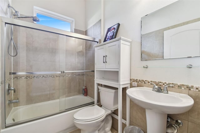 full bathroom with sink, bath / shower combo with glass door, and toilet