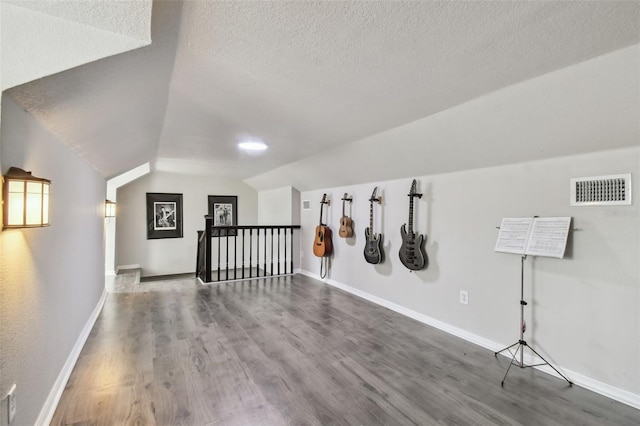 bonus room with a textured ceiling, vaulted ceiling, and wood-type flooring