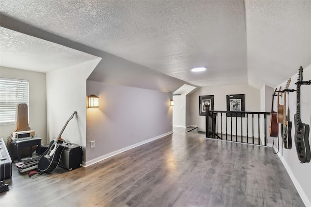 additional living space with lofted ceiling, a textured ceiling, and dark hardwood / wood-style flooring