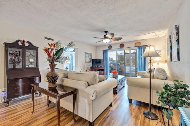 living room featuring ceiling fan, wood-type flooring, and a textured ceiling