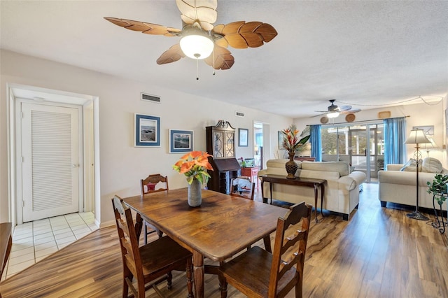 dining room with light hardwood / wood-style floors, a textured ceiling, and ceiling fan