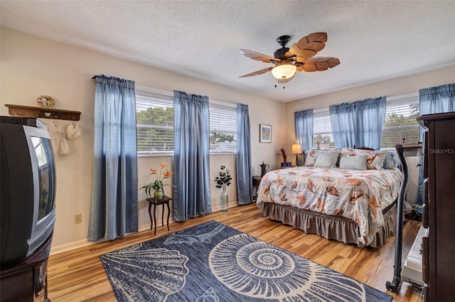 bedroom with light hardwood / wood-style floors, a textured ceiling, and ceiling fan