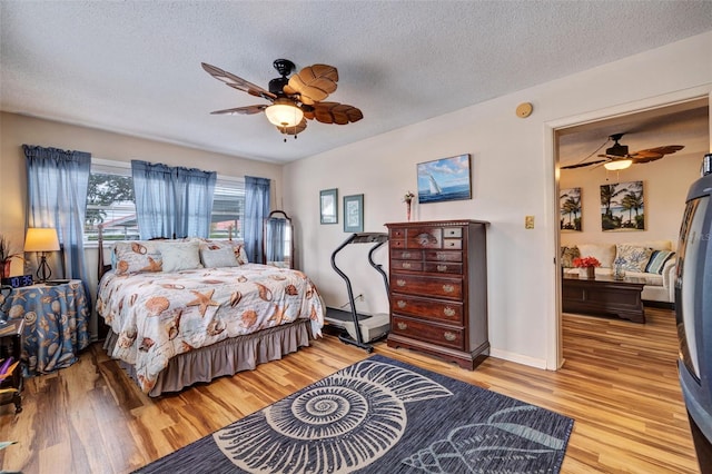 bedroom with light hardwood / wood-style floors, a textured ceiling, and ceiling fan