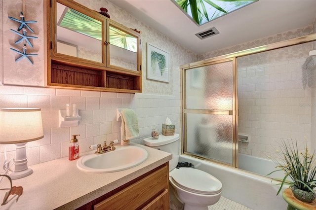 full bathroom featuring enclosed tub / shower combo, tile walls, toilet, a skylight, and vanity