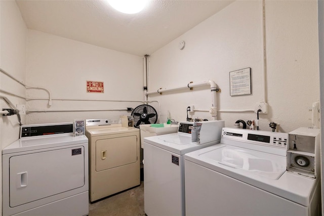 clothes washing area with a textured ceiling and separate washer and dryer