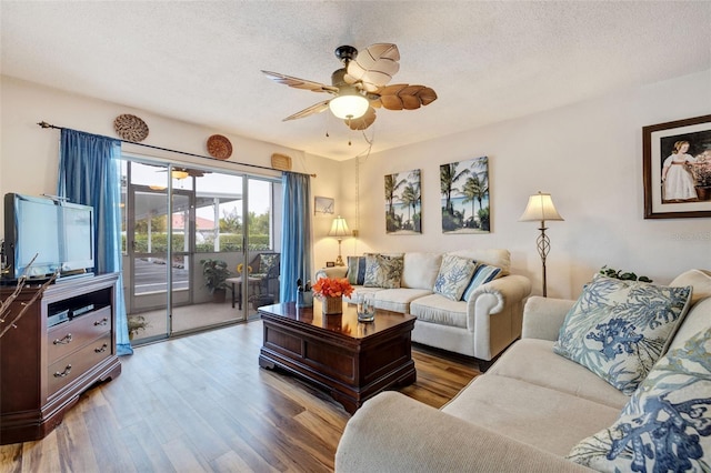 living room featuring a ceiling fan, wood finished floors, and a textured ceiling