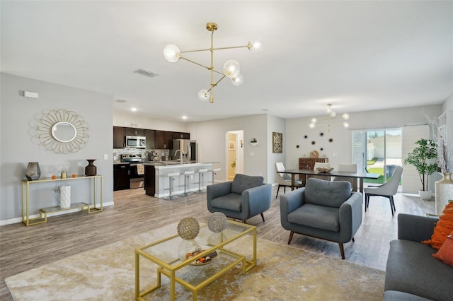 living room featuring a chandelier and light wood-type flooring