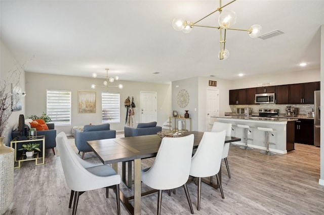 dining space with a notable chandelier and light wood-type flooring