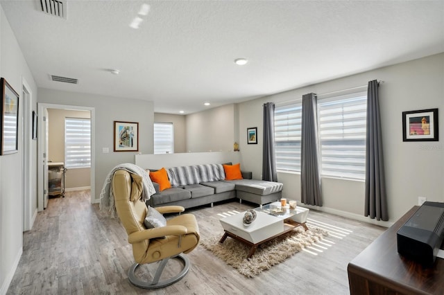 living room with a textured ceiling and light wood-type flooring