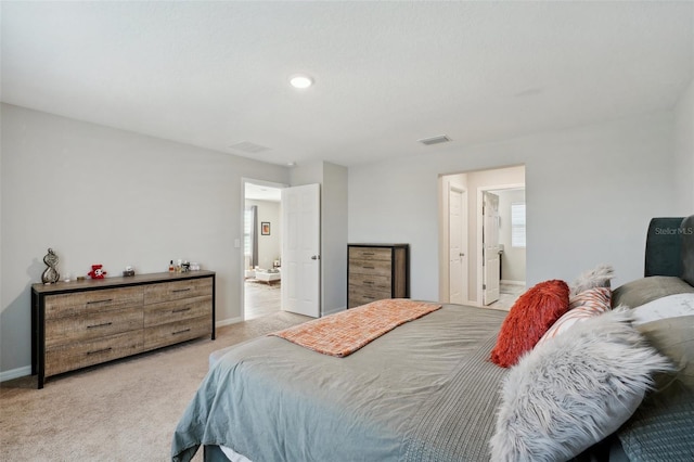 bedroom featuring light colored carpet and ensuite bath