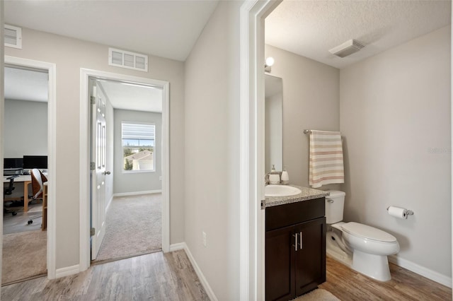 bathroom with vanity, a textured ceiling, toilet, and wood-type flooring