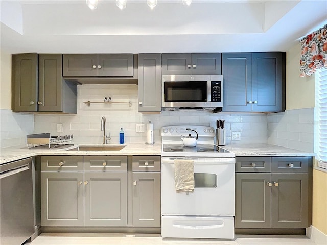 kitchen with light stone countertops, sink, appliances with stainless steel finishes, and tasteful backsplash