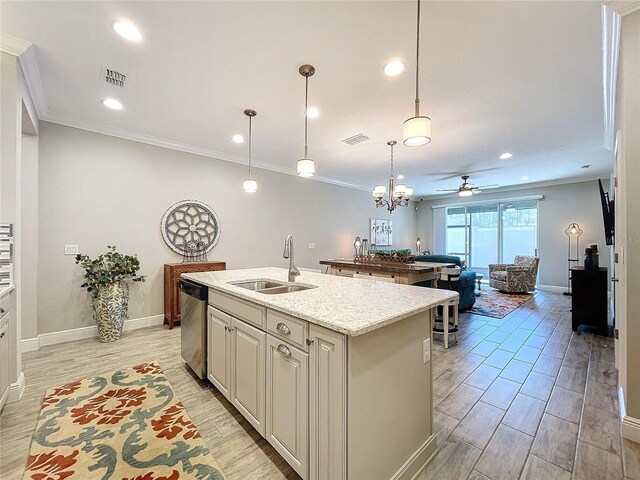 kitchen featuring light stone counters, a kitchen island with sink, stainless steel dishwasher, sink, and decorative light fixtures