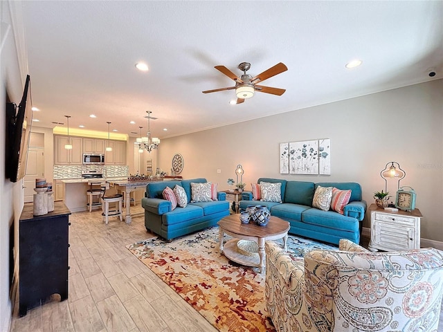 living room featuring ornamental molding and ceiling fan with notable chandelier