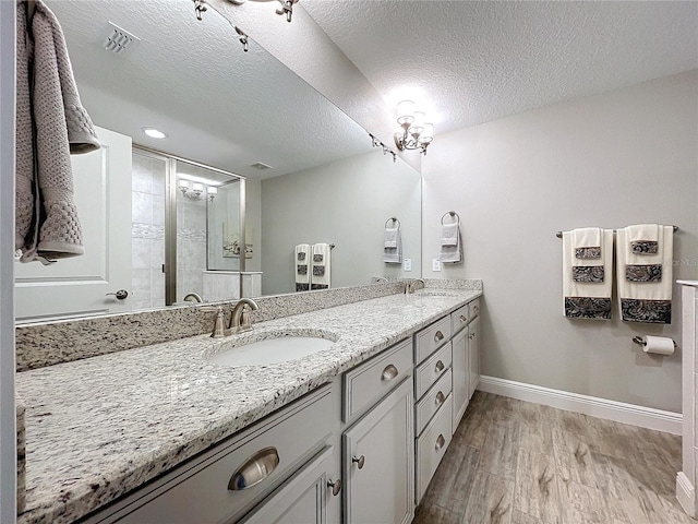 bathroom with vanity, wood-type flooring, a textured ceiling, and an enclosed shower