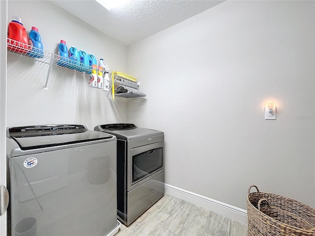 washroom featuring light hardwood / wood-style flooring, washer and dryer, and a textured ceiling