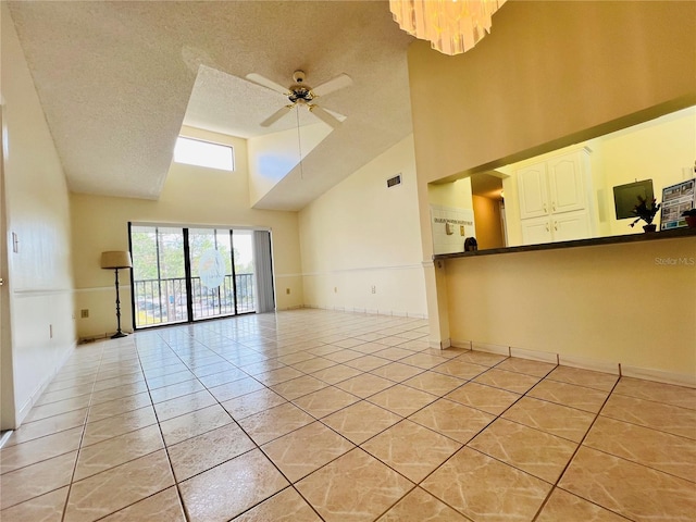 tiled empty room featuring ceiling fan with notable chandelier, a high ceiling, and a textured ceiling