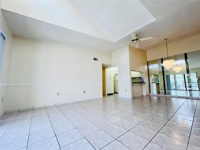 unfurnished room with ceiling fan with notable chandelier and high vaulted ceiling