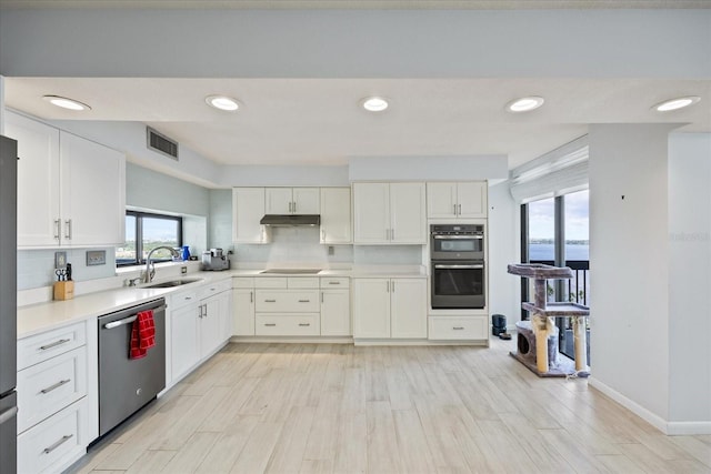 kitchen featuring decorative backsplash, white cabinets, sink, light hardwood / wood-style floors, and stainless steel appliances