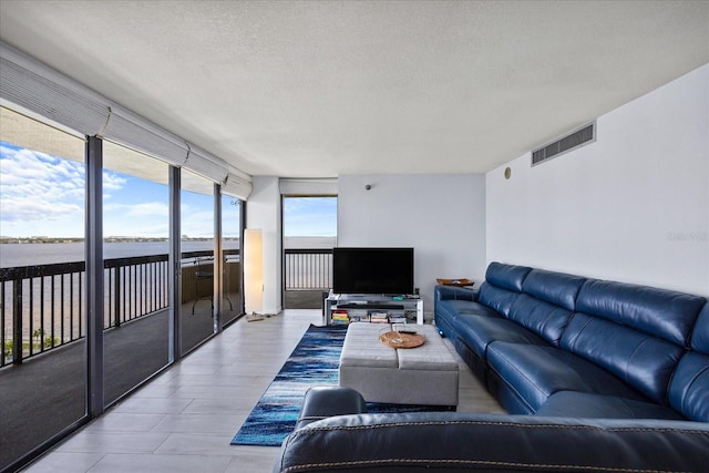 living room with a textured ceiling, floor to ceiling windows, and light wood-type flooring