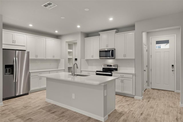 kitchen featuring white cabinets, a kitchen island with sink, light wood-type flooring, sink, and stainless steel appliances