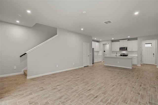 unfurnished living room with sink and light hardwood / wood-style flooring