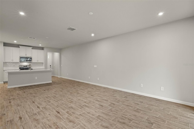 unfurnished living room featuring light hardwood / wood-style floors and sink