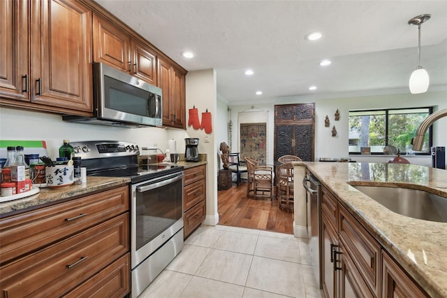 kitchen featuring crown molding, stainless steel appliances, sink, and light stone counters