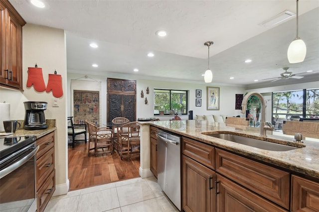 kitchen featuring light stone countertops, light tile patterned flooring, appliances with stainless steel finishes, sink, and hanging light fixtures