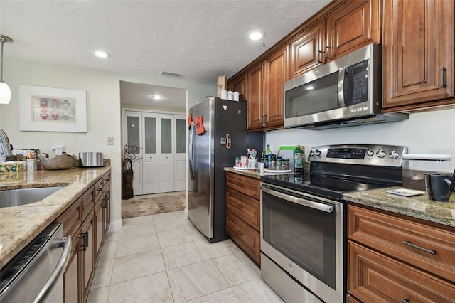 36750 US Highway 19 N Unit 05213, Palm Harbor, FL 34684 - kitchen with a sink, brown cabinets, visible vents, light stone countertops, and appliances with stainless steel finishes