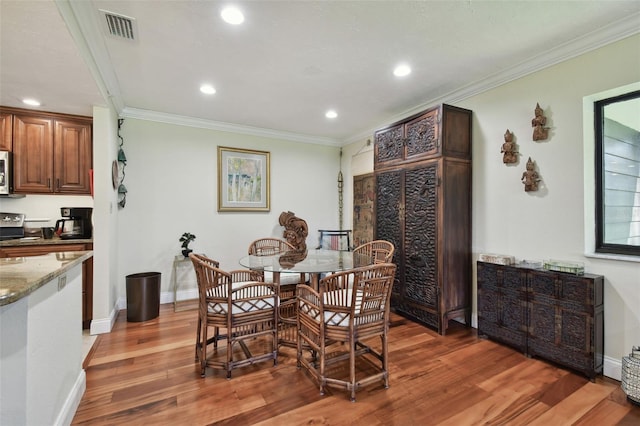 dining area with ornamental molding and dark hardwood / wood-style floors