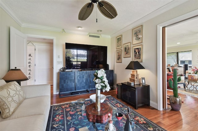 living room featuring a textured ceiling, crown molding, wood-type flooring, and ceiling fan